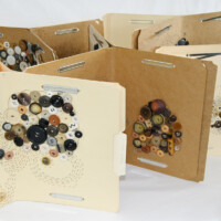 Used manila folders, buttons, thread, ink, pebbles, metal letters, metal clasps. Dimensions variable, 2009